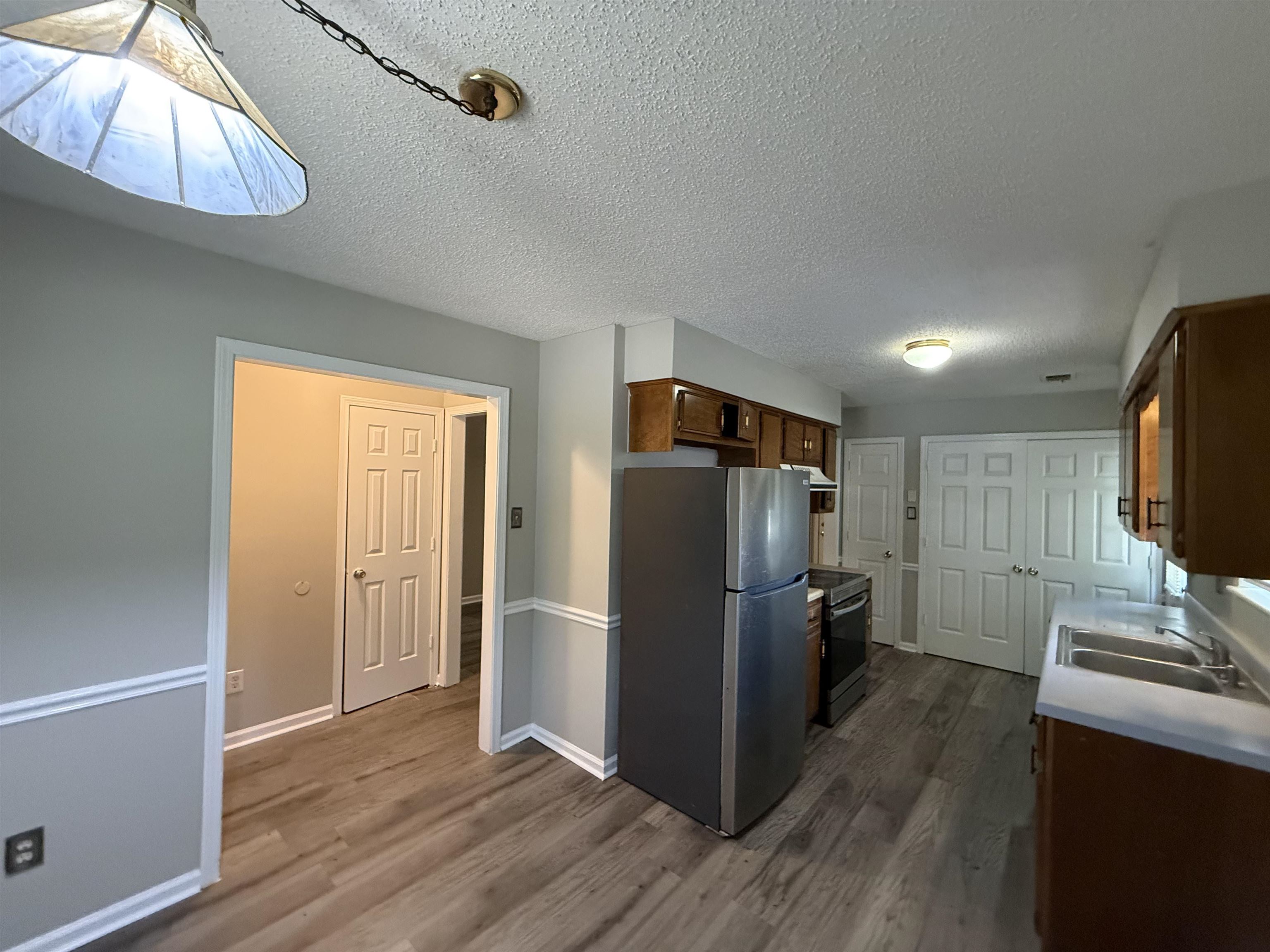6420 Saginaw Road Memphis, TN 38134 - Photo 11 of 38 Kitchen featuring wood-finish flooring, warm wood cabinetry, a double basin sink, and a stainless steel refrigerator