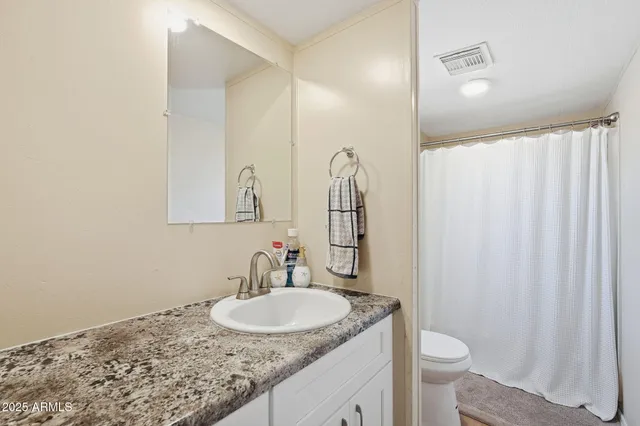 a bathroom with a granite countertop sink toilet and a mirror