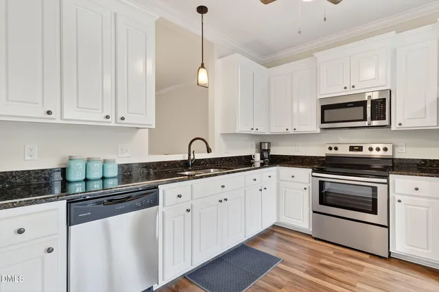 a kitchen with granite countertop white cabinets white stainless steel appliances with a sink and dishwasher