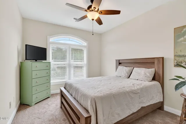 a bedroom with a bed and a flat tv screen on dresser