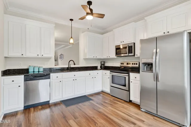 a kitchen with granite countertop a refrigerator a sink and white cabinets