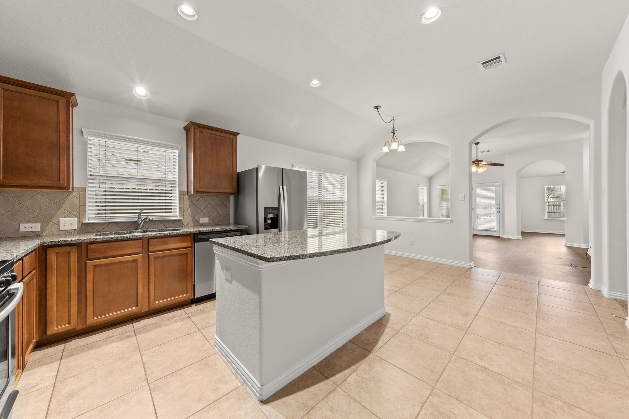 411 Tascate Street Georgetown, TX 78628 - Photo 11 of 41 A well-appointed kitchen features a central island with granite counters, seamlessly connecting to an airy living space.