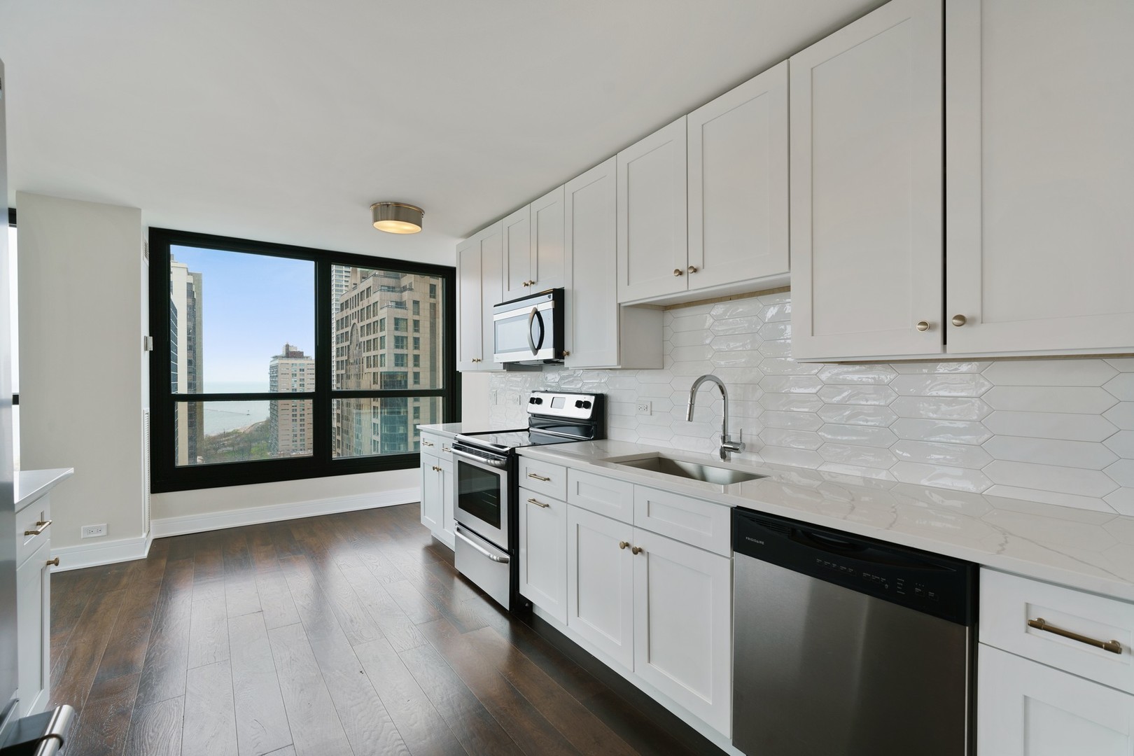 1030 North State Street, Unit 13E Chicago, IL 60610 - Photo 9 of 30 a kitchen with stainless steel appliances granite countertop a stove a sink dishwasher and white cabinets with wooden floor next to windows