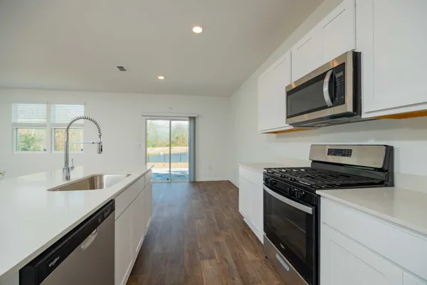 a kitchen with stainless steel appliances granite countertop a sink and a stove top oven
