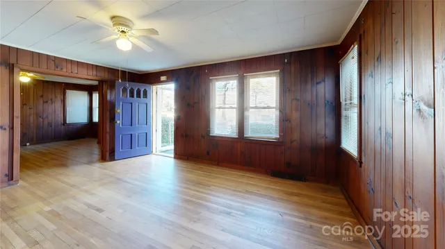 a view of an empty room with a window and wooden floor