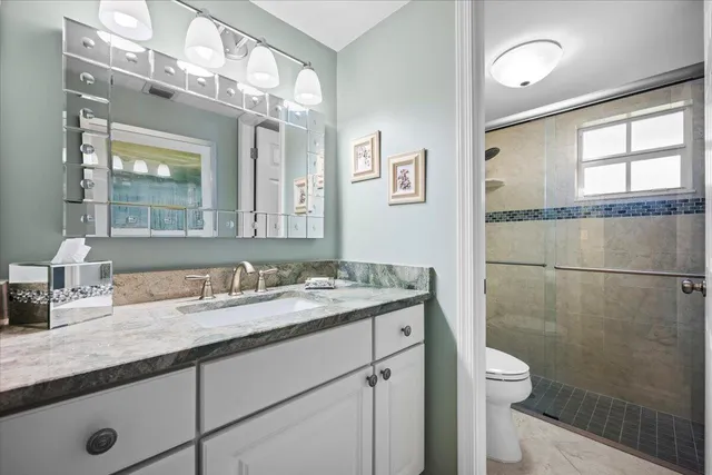 a bathroom with a granite countertop sink mirror vanity and toilet