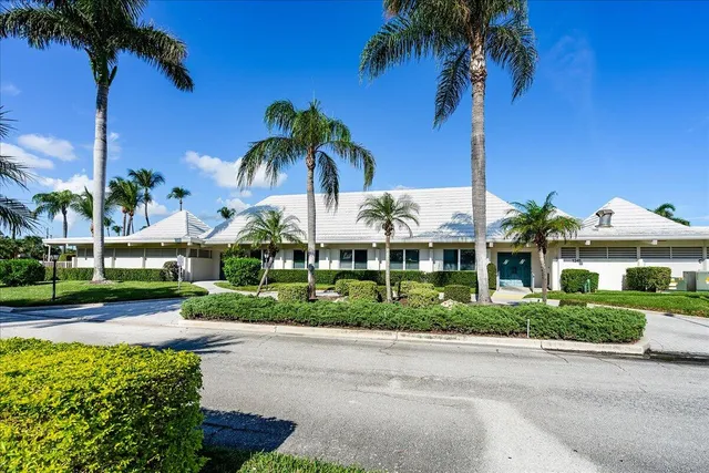 a front view of a house with a yard and palm trees