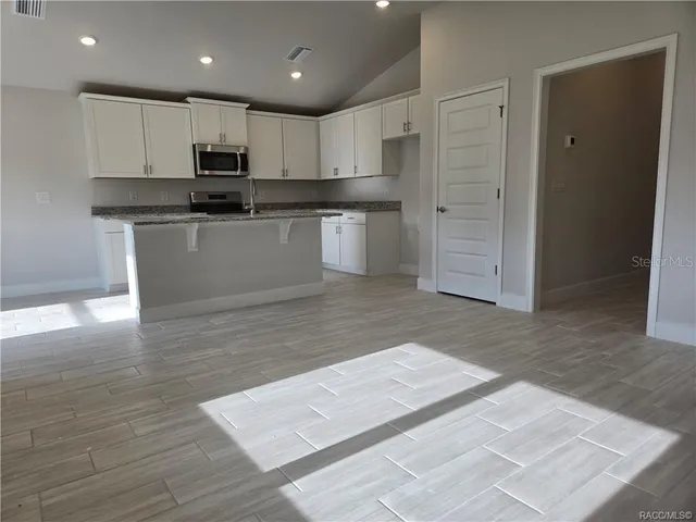 a kitchen with stainless steel appliances granite countertop a stove a sink and a microwave