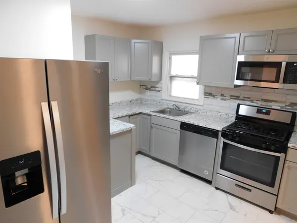 a kitchen with granite countertop a refrigerator stove and microwave