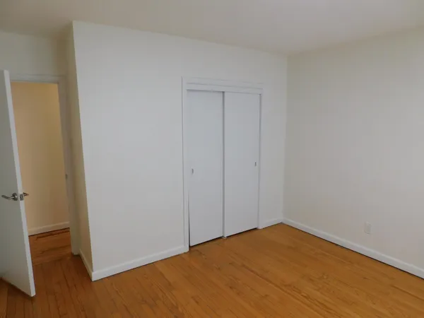 a view of empty room with wooden floor