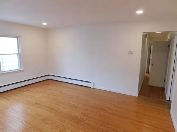 a view of an empty room with wooden floor and a window
