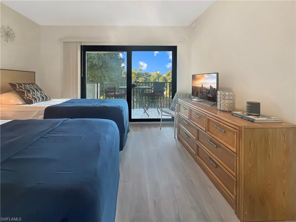600 Neapolitan Way, Unit 342 Naples, FL 34103 - Photo 21 of 50 a bedroom with a bed and a flat tv screen on dresser