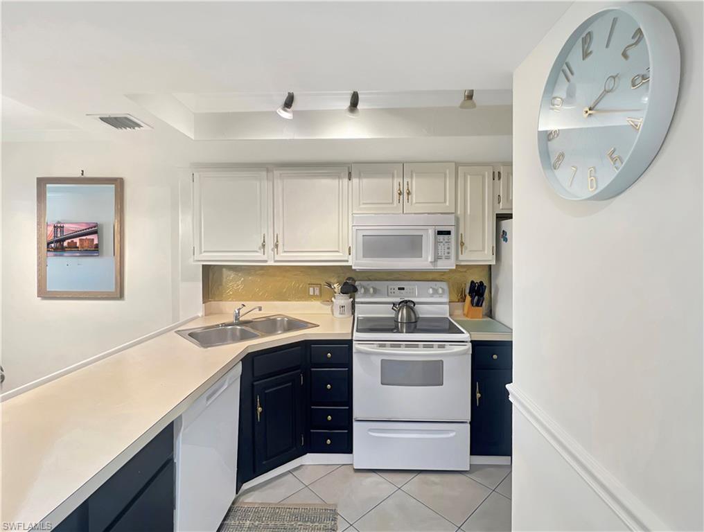 600 Neapolitan Way, Unit 342 Naples, FL 34103 - Photo 4 of 50 a kitchen with a sink dishwasher and a stove with wooden floor