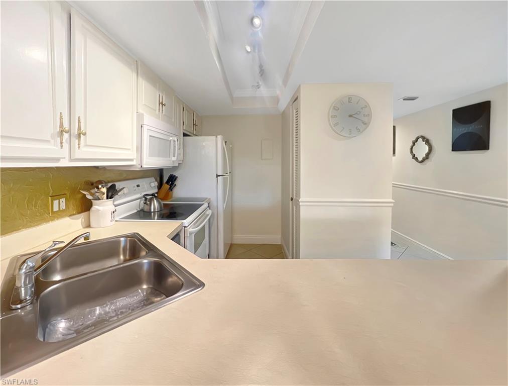 600 Neapolitan Way, Unit 342 Naples, FL 34103 - Photo 6 of 50 a kitchen with a refrigerator sink and cabinets