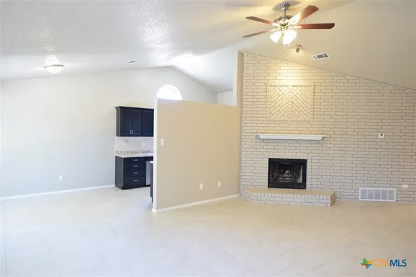 a view of an empty room with a fireplace and a window