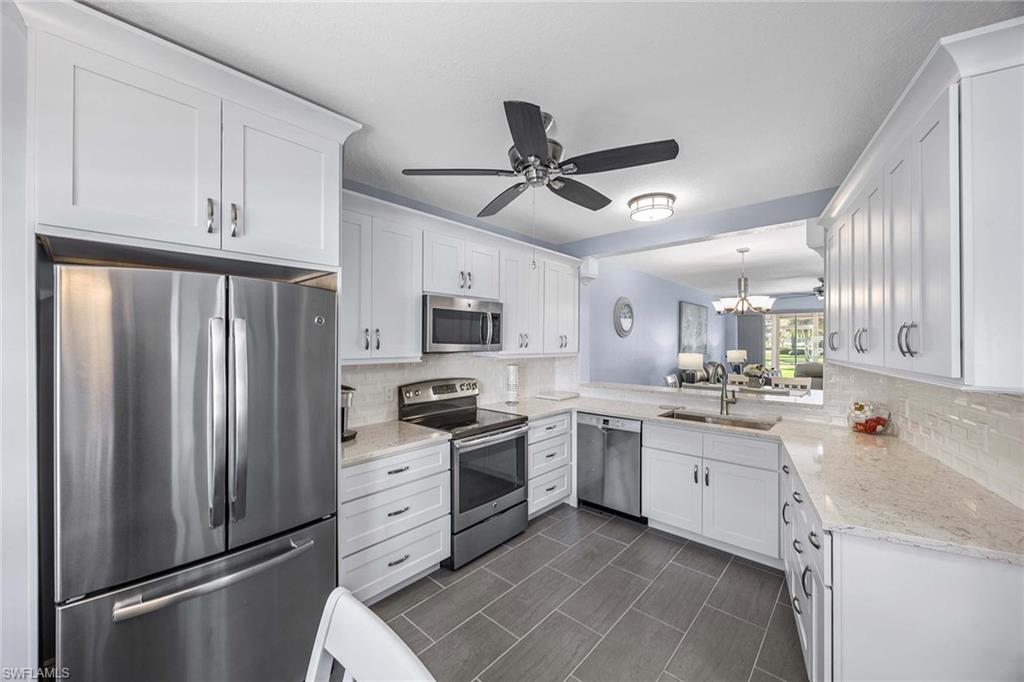 9022 Michael Circle, Unit 3 Naples, FL 34113 - Photo 14 of 29 a kitchen with stainless steel appliances a refrigerator sink and cabinets
