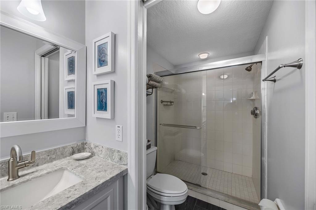 9022 Michael Circle, Unit 3 Naples, FL 34113 - Photo 20 of 29 a bathroom with a granite countertop sink toilet and shower