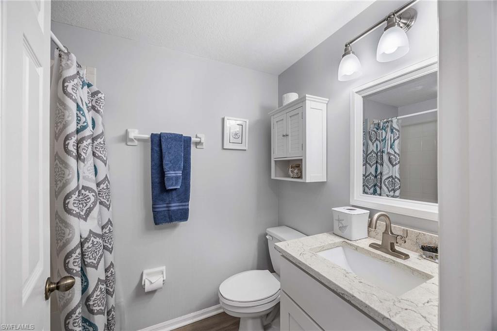 9022 Michael Circle, Unit 3 Naples, FL 34113 - Photo 22 of 29 a bathroom with a granite countertop toilet sink and mirror