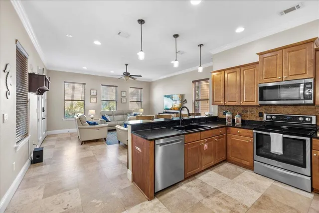 a kitchen with stainless steel appliances granite countertop a stove top oven a sink dishwasher a dining table and chairs with wooden floor