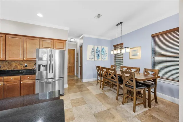 a kitchen with granite countertop a refrigerator a stove a dining table and chairs