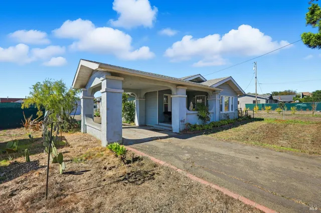 a front view of a house with a yard and potted plants