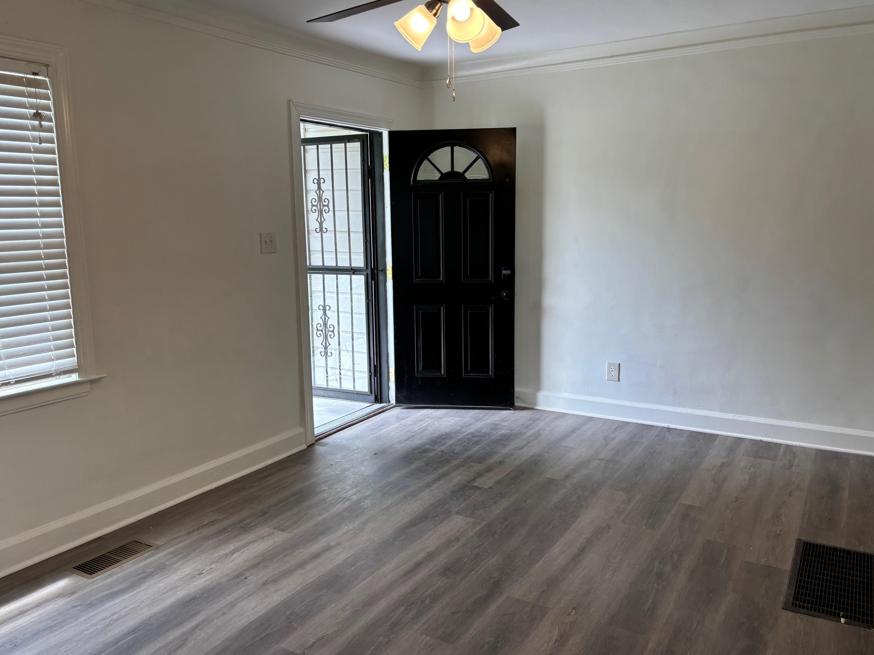 an empty room with wooden floor and windows