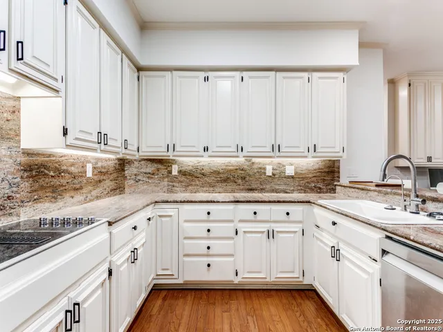 a kitchen with granite countertop white cabinets and a sink