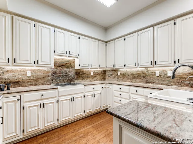 a kitchen with granite countertop white cabinets and sink