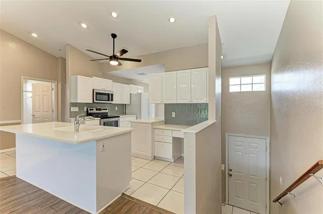 a kitchen with kitchen island white cabinets and refrigerator