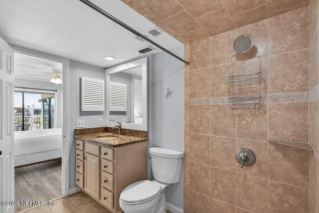 a bathroom with a granite countertop toilet a sink a mirror and shower