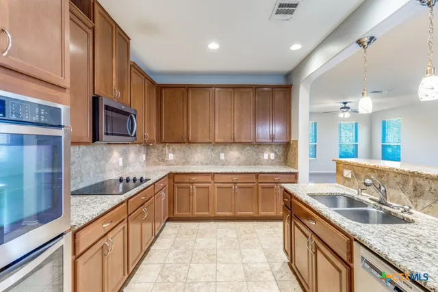 a kitchen with granite countertop sink stainless steel appliances and cabinets