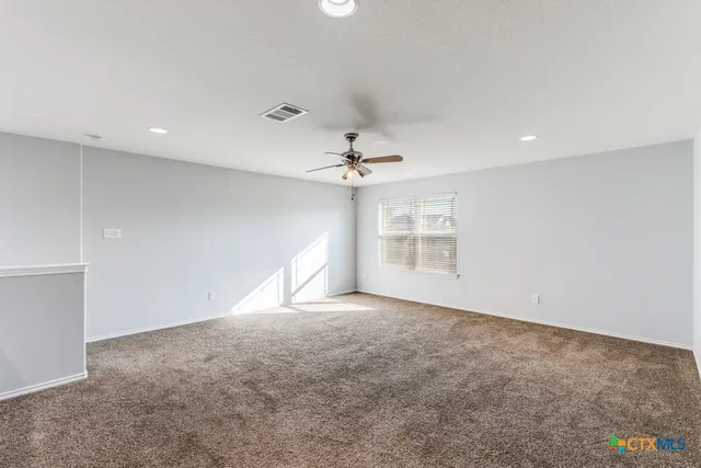 an empty room with a ceiling fan and window