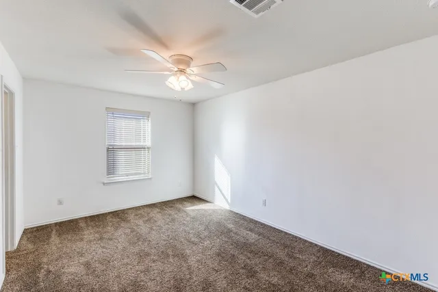 an empty room with a window and a ceiling fan