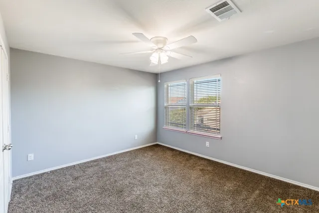 an empty room with windows and fan