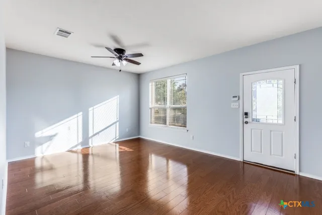 a view of an empty room with window and wooden floor