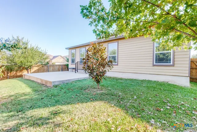 a view of a house with backyard and a tree