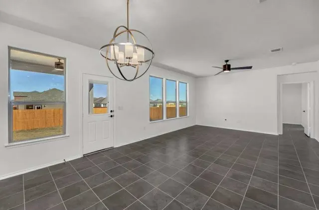 an empty room with windows and fan