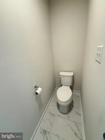 a white toilet sitting next to a white wall