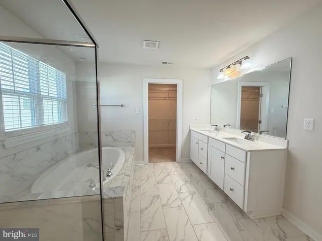 a spacious bathroom with a double vanity sink a mirror and a bathtub
