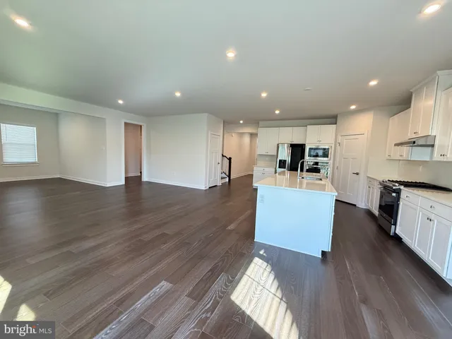 a view of kitchen with kitchen island wooden floor center island and stainless steel appliances