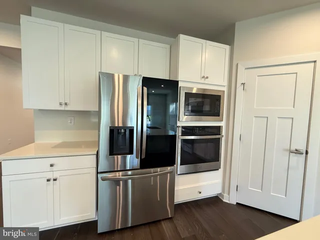 a kitchen with stainless steel appliances white cabinets and wooden floors