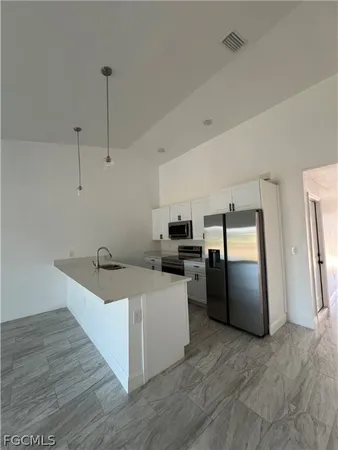 a kitchen with stainless steel appliances granite countertop a refrigerator a sink a stove and a wooden floors