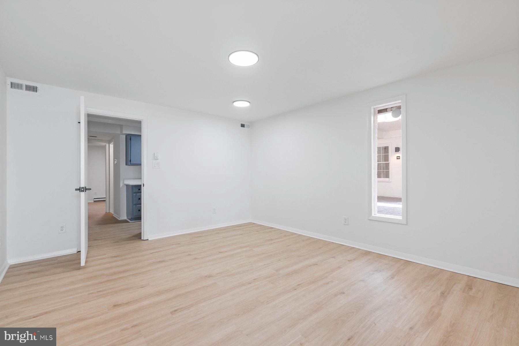 207 South Patrick Street, Unit 104 Alexandria, VA 22314 - Photo 4 of 33 an empty room with wooden floor and windows