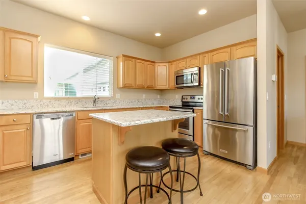 a kitchen with stainless steel appliances granite countertop a sink stove refrigerator and a window