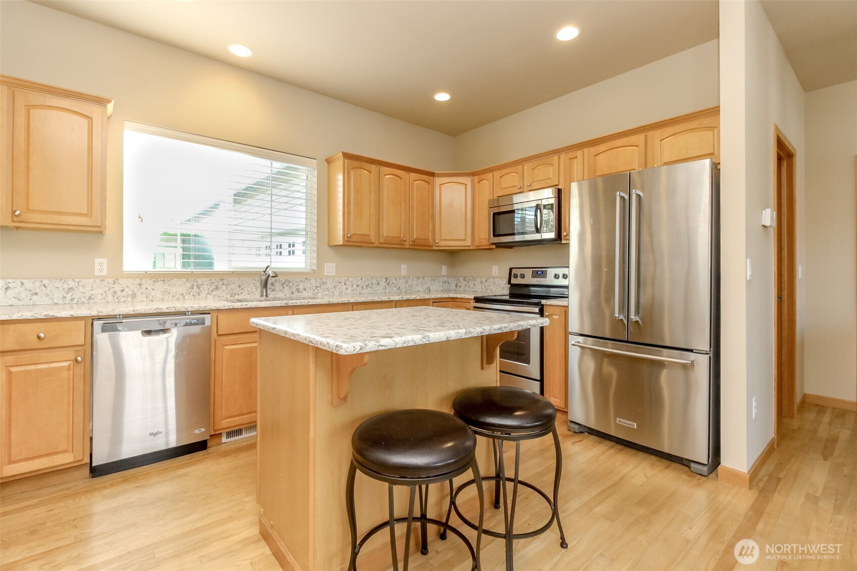 1113 O'Farrell Lane Northwest Orting, WA 98360 - Photo 11 of 36 a kitchen with granite countertop stainless steel appliances a refrigerator a stove a sink and white cabinets with wooden floor