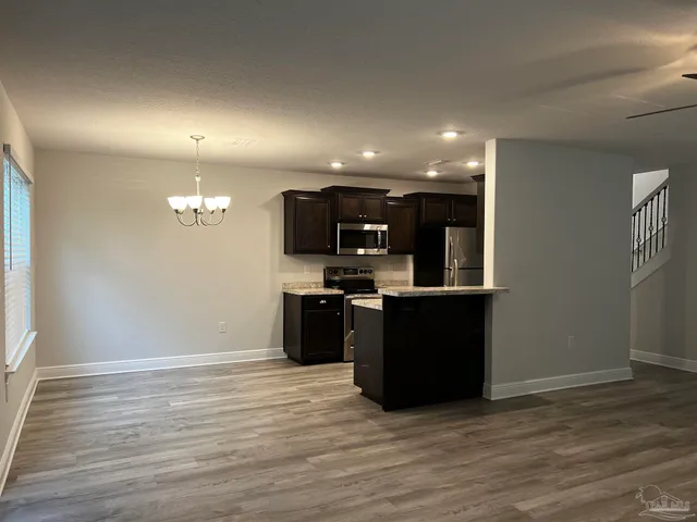 a kitchen with stainless steel appliances kitchen island granite countertop a refrigerator and a wooden floors