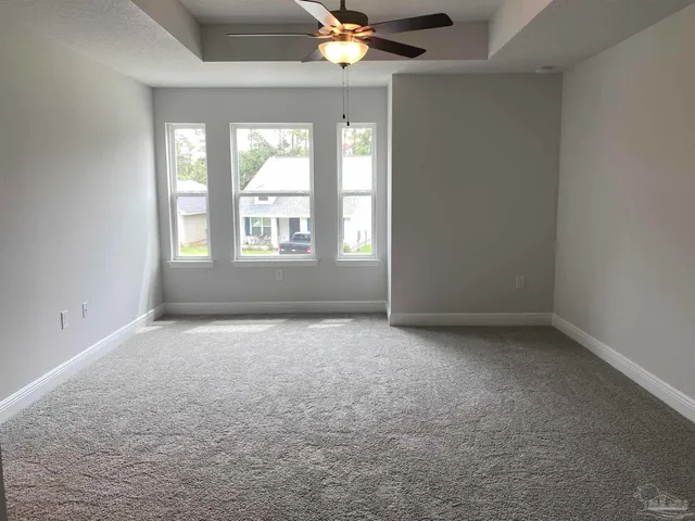 an empty room with a chandelier fan and windows