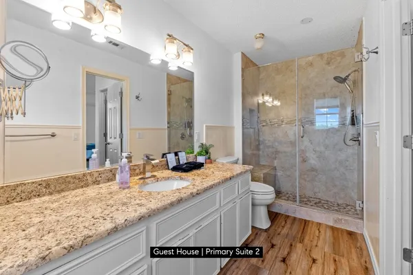 a bathroom with a granite countertop sink a toilet a mirror and shower