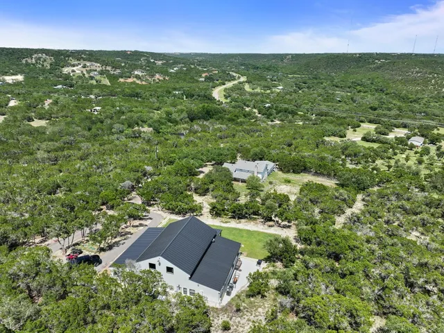 an aerial view of residential houses with outdoor space and trees