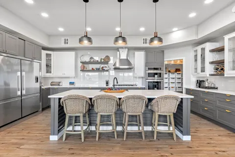 a kitchen with stainless steel appliances granite countertop a dining table chairs refrigerator and microwave